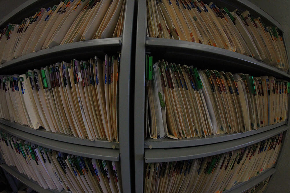 Wide-angle image of shelves of patient files, all with multi-colored tabs